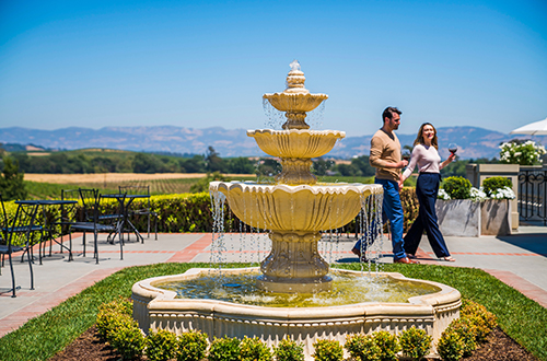 A couple walking near the impressive fountain on the north terrace of Domaine Carneors